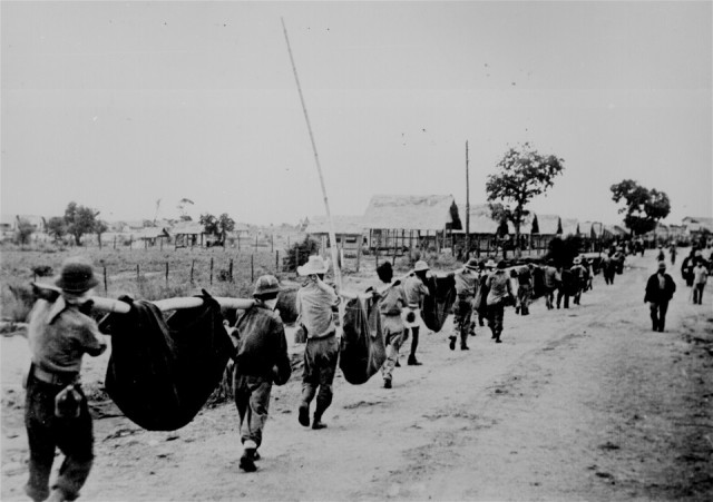 Cette photo, capturée aux Japonais, montre des prisonniers américains utilisant des litières improvisées pour transporter ceux de leurs camarades qui, par manque de nourriture ou d'eau lors de la marche de Bataan, tombaient le long de la route. Philippines, mai 1942. 208-AA-288BB-2. (ww2_131.jpg) Au moment de sa publication, cette photo a été identifiée comme représentant des morts et des blessés portés par des camarades prisonniers pendant la Marche de la mort de Bataan en avril 1942 ... Des informations ultérieures provenant d'archivistes militaires, de la National Archives and Records Administration et de prisonniers survivants, suggèrent fortement que cette photo pourrait en fait représenter un détail d'enterrement au Camp O'Donnell.