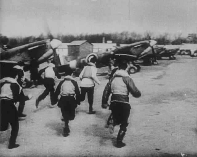 British pilots running towards their fighters (Spitfires) on the air-raid alarm.