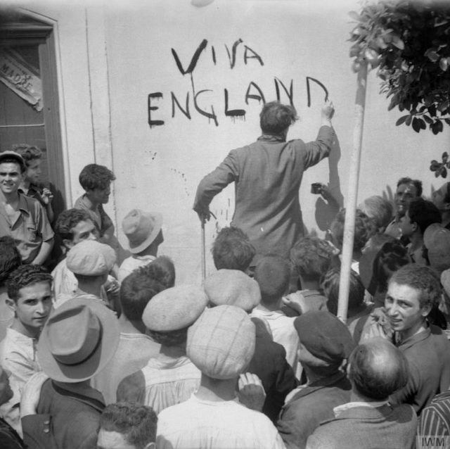 Civilian resident of Misterbianco, near Catania, paints the slogan ‘Viva England’ on a wall after the village had been occupied by the Eighth Army. [© IWM (NA 5450)]