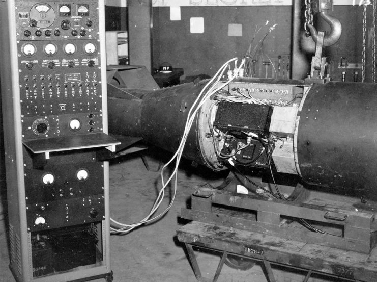 A Little Boy unit checked up to a bank of equipment; possibly to test or charge components within the device.