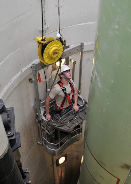 Staff Sgt. Isaiah Miller operates a guided missile maintenance platform to navigate around a mock-up of a Minuteman III aging nuclear missile during a maintenance exercise