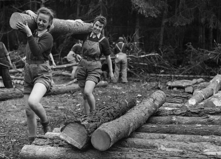 Two women carrying a tree trunk over their shoulders