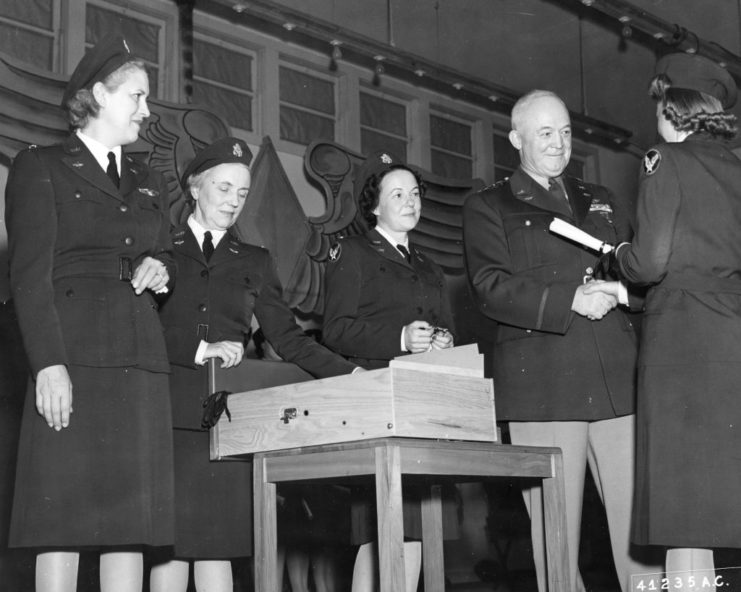 General Henry H. Arnold presenting a trainee with their diploma as officials watch on