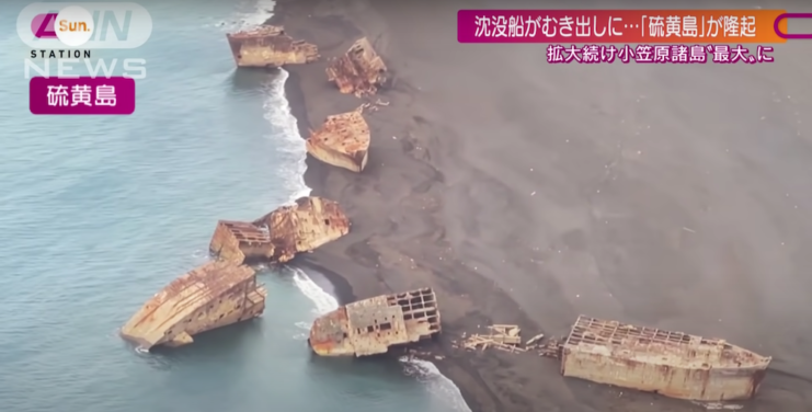 Broken ship hulks spread across the shore of Iwo Jima