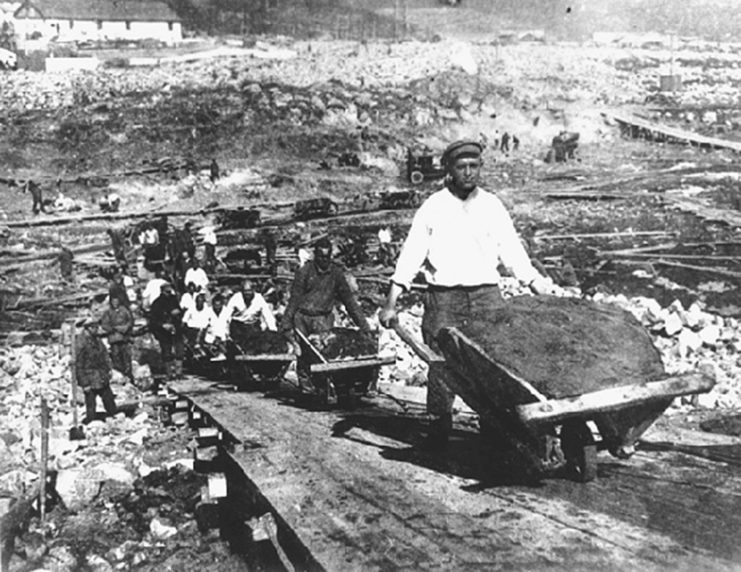 Kulaks walking in a row while pushing wheelbarrows