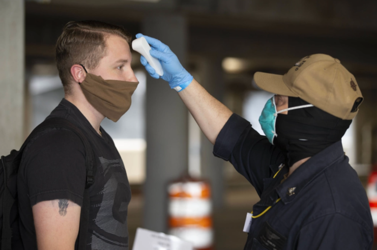 Male Navy sailor having his temperature taken by a comrade