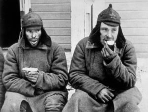 Two Russian prisoners eating their rations in a Finnish POW camp behind the lines.  (Photo Credit: Central Press/Getty Images)