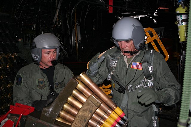 Master Sgt. Randy Scanian watching R. Lee Ermey load a 40 mm gun