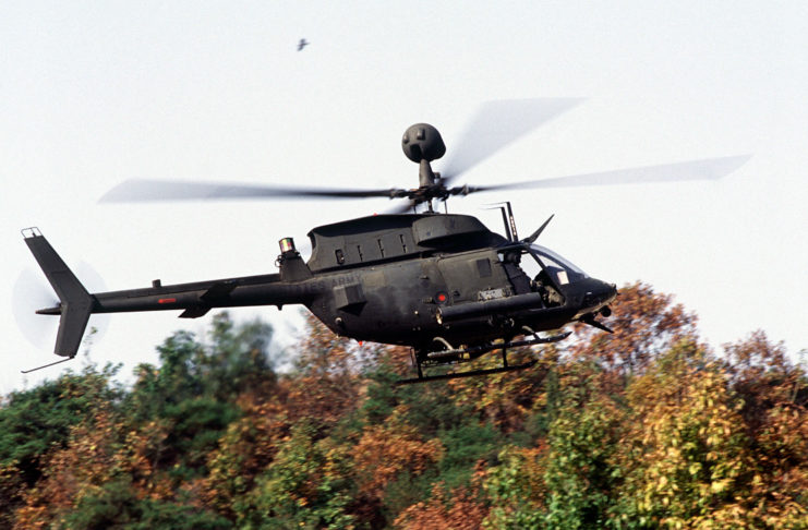 OH-58 Kiowa mid-flight at treetop height