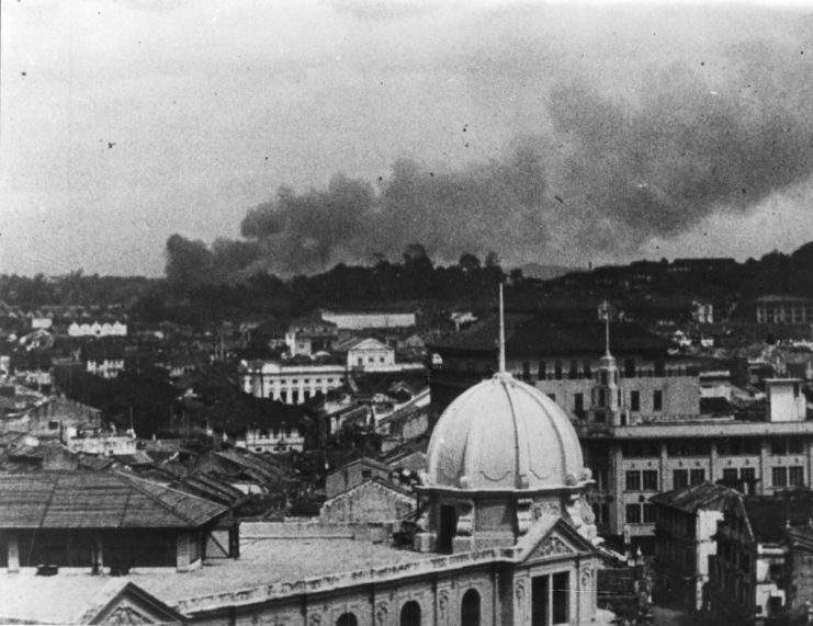 A plume of smoke rises over a cityscape in Singapore, circa 1942.