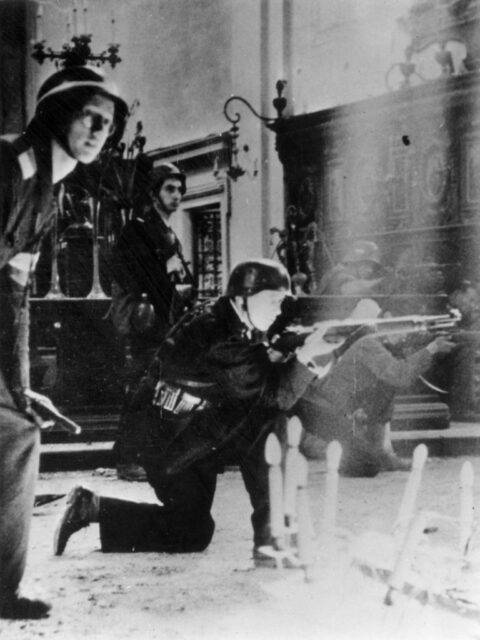 Members of the Polish Resistance standing in a building in uniform and with weapons