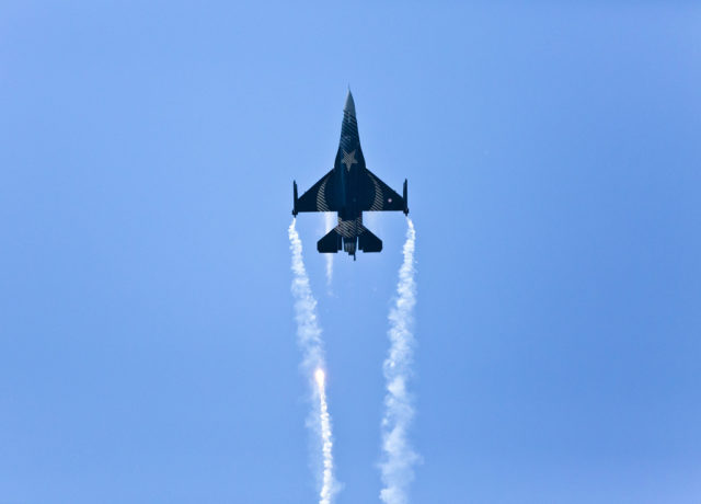 An F-16 fighter jet against a bright blue sky