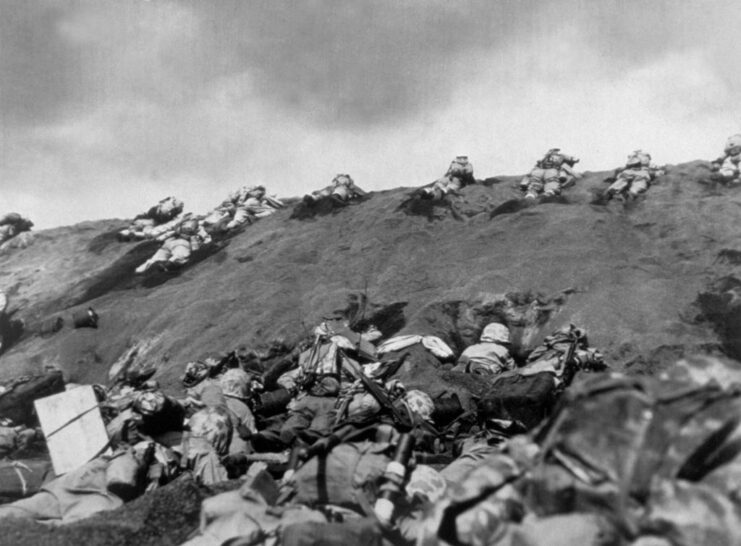 Members of the 5th Marine Division crawling up a beach on Iwo Jima