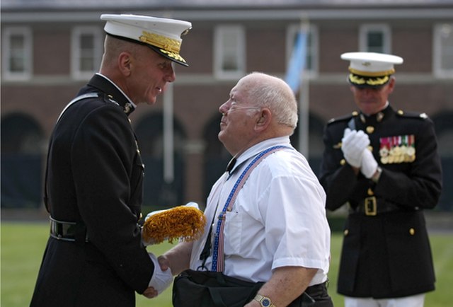 Jacklyn Lucas and Michael W. Hagee shaking hands, while another US Marine stands near them