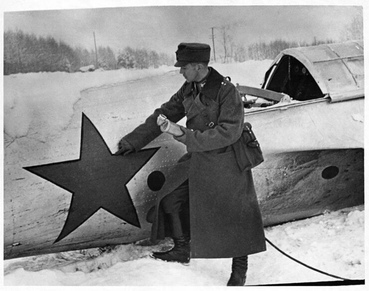 Finnish radio announcer standing next to a downed Soviet aircraft