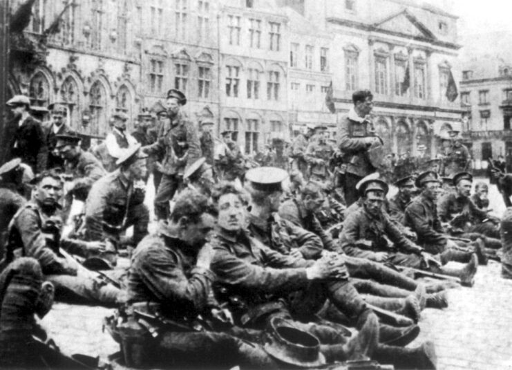 Members of A Company, 4th Battalion, Royal Fusiliers sitting in the middle of a street in Mons, Belgium