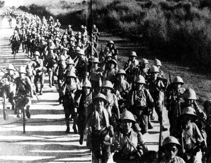 Japanese soldiers marching together down a road