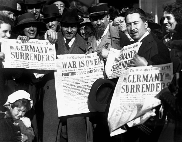 Group holding up newspapers announcing Germany's surrender