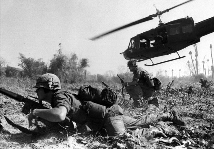 Bell UH-1D Iroquois hovering over two American infantrymen