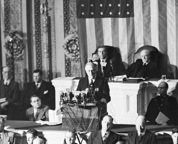 Franklin D. Roosevelt standing at a podium, with political officials sitting around him