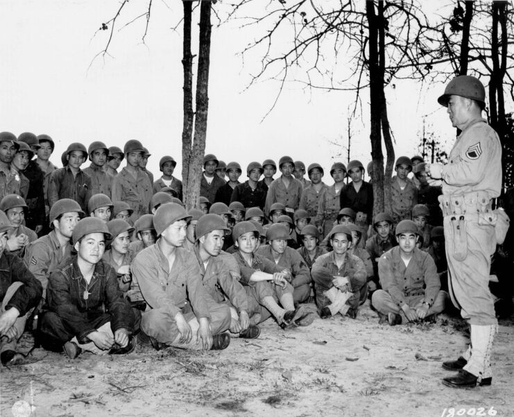 Members of the 100th Infantry Battalion sitting outside in uniform