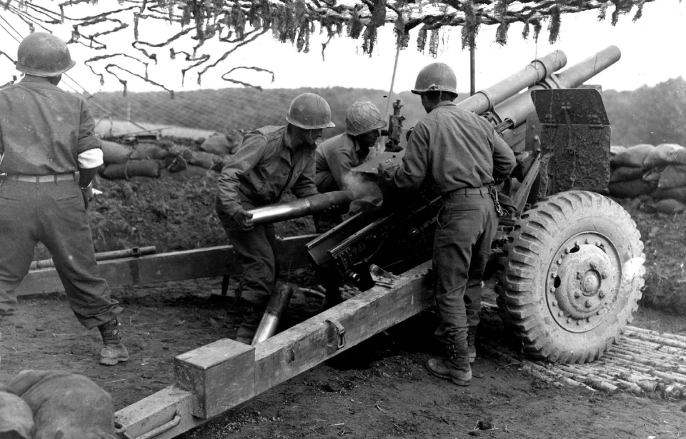 Members of the 522nd Field Artillery Battalion loading 105 mm shells into a weapon