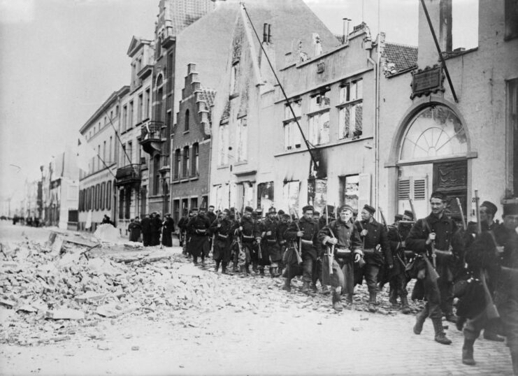 Belgian troops marching through a rubble-strewn street