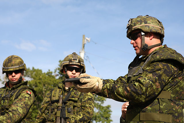 Three members of A Company, 3rd Battalion, Royal 22nd Regiment standing together, with one holding a Browning Hi-Power