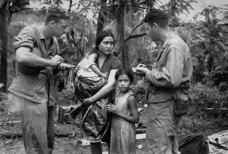 Robert "Pepper" Martin and Howard Handleman speaking to a Chamorro woman who is standing with her children