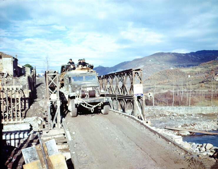 US Army truck crossing a bridge running over a small river