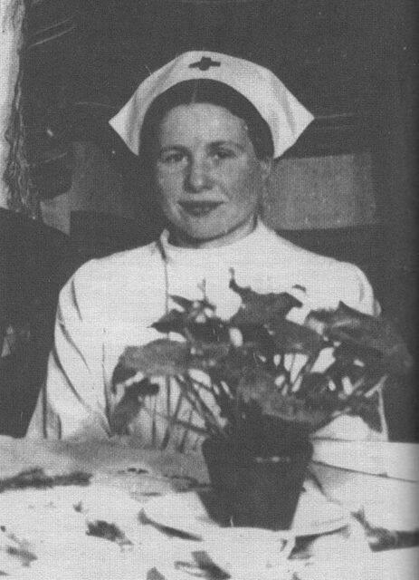 Irena Sendler sitting at a table while dressed as a nurse