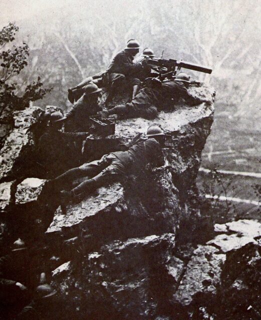 Group of Italian machine gunners aiming weapons from a rocky ledge
