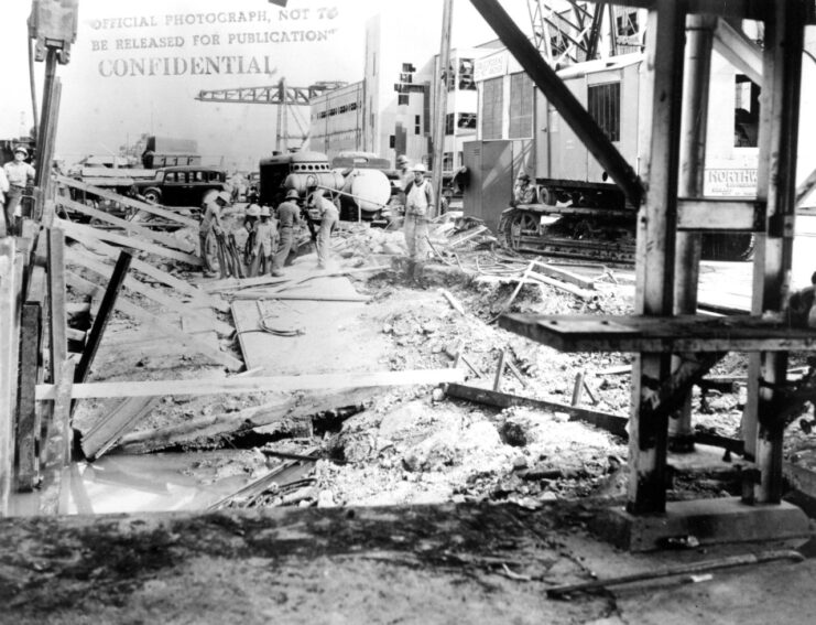 Workers standing among piles of rubble