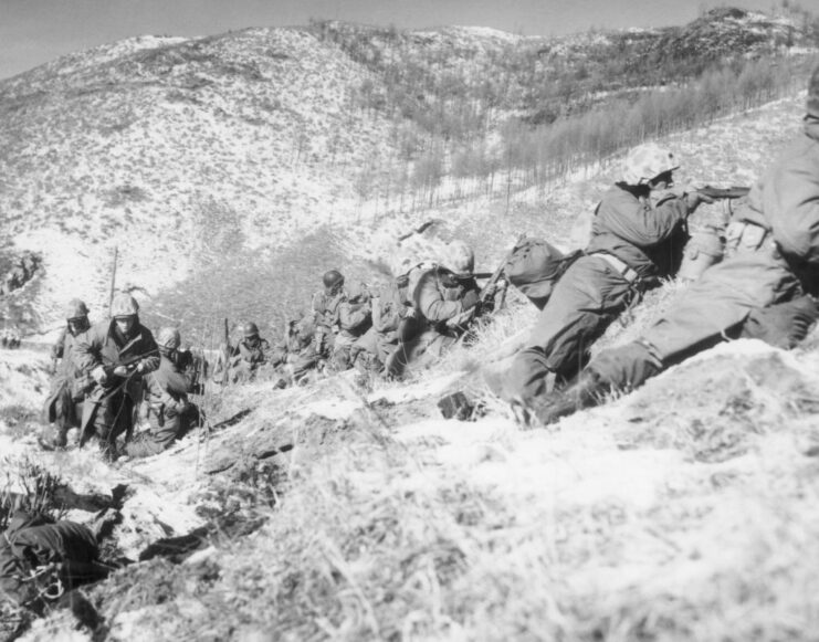 US Marines lying on the ground, along the edge of a hill