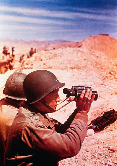 George Patton looking through binoculars in the middle of the desert