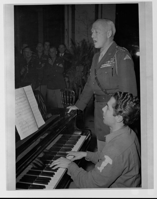 George Patton singing while another soldier plays the piano