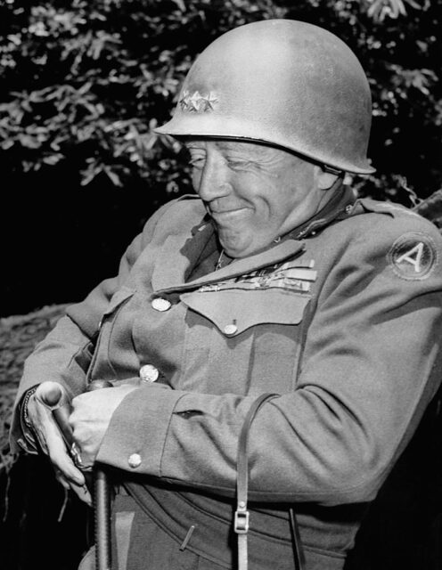 George Patton grinning while sitting in a chair