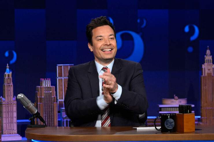 Jimmy Fallon sitting at his desk on the set of 'The Tonight Show Starring Jimmy Fallon'