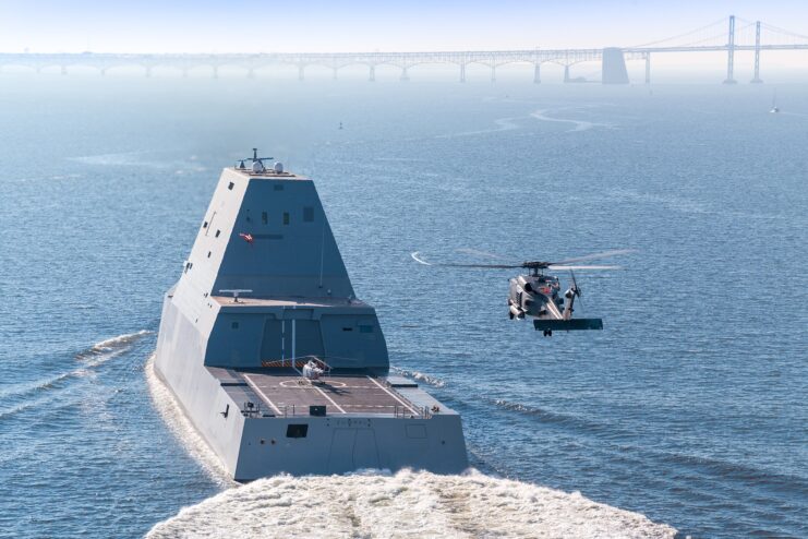 Helicopter flying alongside the USS Zumwalt (DDG-1000) as she leaves port