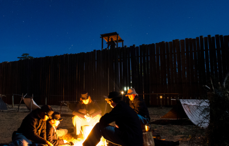 Volunteers reenact prisoners at Andersonville huddling around a fire.