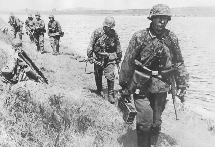 Waffen-SS troops walking along a riverbank