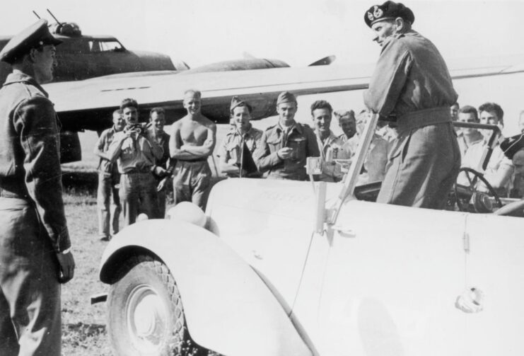 Soldiers standing around Bernard Montgomery, who is standing in a topless car