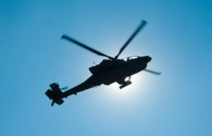 An AH-64 Apache helicopter hovers in front of the sun and conducts movement drills as part of a maintenance test flight in Kunduz province, Afghanistan