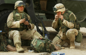 U.S. Military Police Lance Corporals Tony Lantrip (L), from Clarksville, Indiana, and Scott Roberson of Hamilton, Ohio eat Meals Ready to Eat (MRE) at a government highway checkpoint March 19, 2003 in the desert of Kuwait.