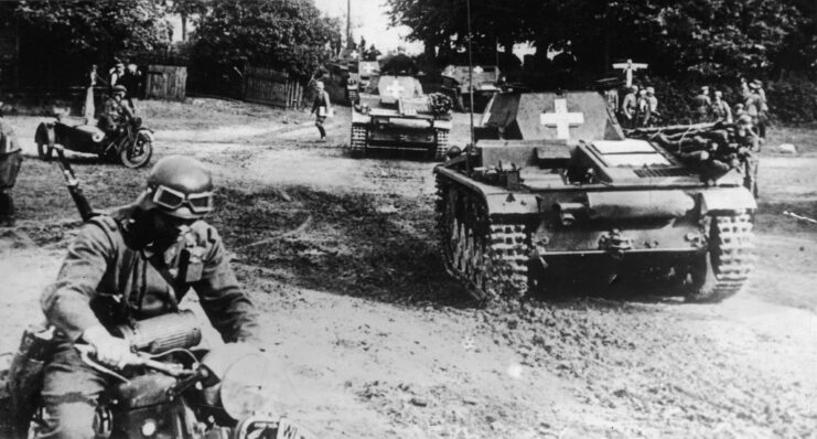 Tanks and German soldiers on motorcycles moving along a road