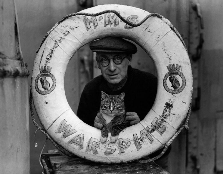 Sailor and cat peeking through the middle of a life preserver aboard the HMS Warspite (03)