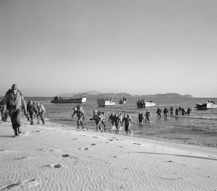 Members of the 1st Marine Division walking to shore from landing craft
