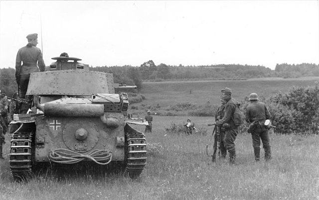 German soldier standing on a Panzer 38(t), while others stand nearby