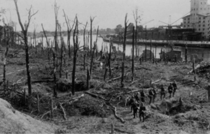 German soldiers walking through the muddy remains of a wooded area