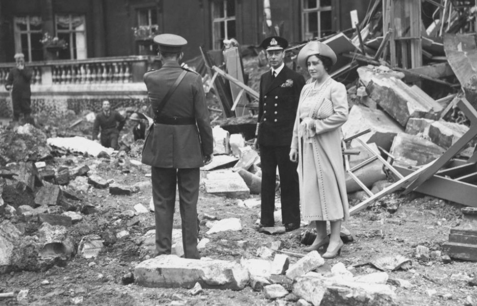 King George VI and Elizabeth, the Queen Mother standing with a man near a damaged part of Buckingham Palace